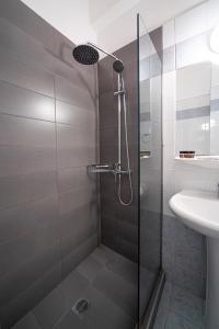una ducha con una puerta de cristal junto a un lavabo en Hotel Cokkinis, en Mégara