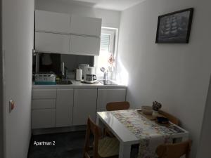 a small kitchen with a table and a white counter top at Apartment One in Rab