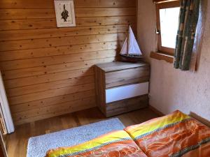 1 dormitorio con pared de madera, cama y ventana en Ferienhaus Möwenherz, en Pruchten