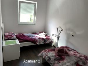 a bedroom with two beds and a desk and a window at Apartment One in Rab