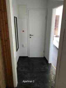 un pasillo con una puerta blanca y una habitación en Apartment One en Rab