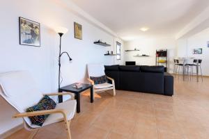 a living room with a black couch and chairs at Mirador del Roque in Orzola