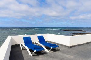 two blue chairs sitting on a ledge overlooking the ocean at Mirador del Roque in Órzola