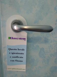 un cartello sulla porta del bagno con maniglia di Hotel Ferrari a Chiavari