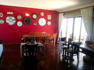 una sala da pranzo con parete rossa e orologi di 12 on Beach Guest House a Saldanha