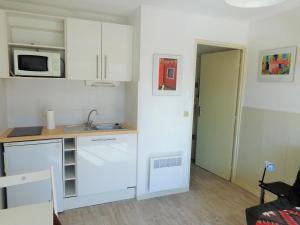 eine kleine Küche mit einer Spüle und einer Mikrowelle in der Unterkunft STUDIO 2 PERS QUARTIER DES PLAGES DE LA CORNICHE in Sète