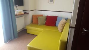a yellow couch with colorful pillows on it in a room at Villa Baltic Chałupy - Apartament nr 1 in Chałupy