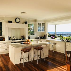 a kitchen with white cabinets and a clock on the wall at Jetty Splendour Guest Bedroom with Bathroom en-suite B'nB in Coffs Harbour