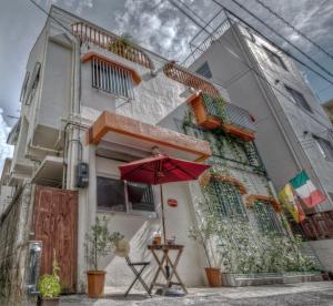 a house with a red umbrella in front of it at La Passione Boutique B&B in Naha