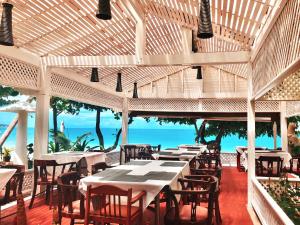 un ristorante con tavoli e sedie e l'oceano di Sans Souci Samui - SHA Plus a Chaweng Beach