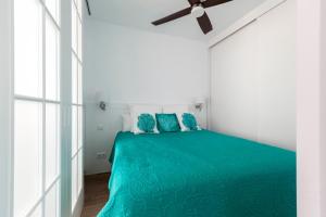 Chamberí Design Loft في مدريد: غرفة نوم بيضاء مع سرير أخضر مع وسائد زرقاء