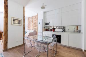 Chamberí Design Loft في مدريد: مطبخ مع طاولة زجاجية و دواليب بيضاء