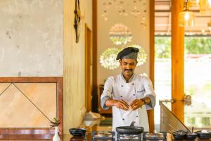 Um homem de pé numa cozinha a preparar comida. em Winter Vale Green Stay Resorts em Vagamon