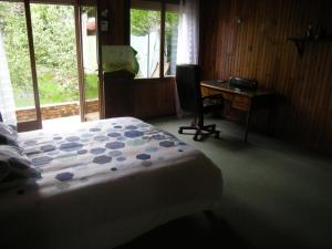 1 dormitorio con cama, escritorio y silla en le clermontain, en Les Clérimois