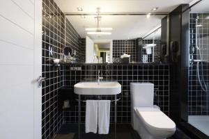 La salle de bains est pourvue de carrelage noir, d'un lavabo et de toilettes. dans l'établissement Europark, à Barcelone