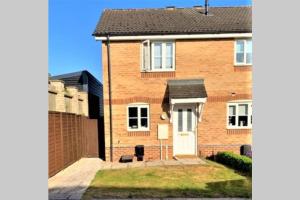 ein Backsteinhaus mit einer weißen Tür und einem Zaun in der Unterkunft Malt House in Newmarket