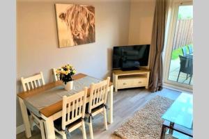 ein Esszimmer mit Tisch und Fernseher in der Unterkunft Malt House in Newmarket
