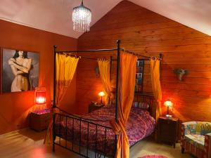 1 dormitorio con cama con dosel en una habitación con paredes de madera en Suzanne's Cottage en Rochehaut