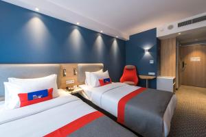 a hotel room with two beds and a red chair at Holiday Inn Express Warsaw - Mokotow, an IHG Hotel in Warsaw