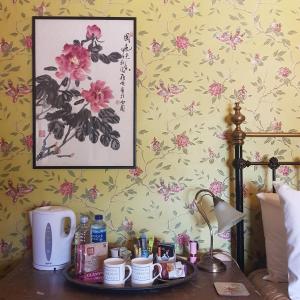 a bedroom with a table with cups and a picture of flowers at Victoria House in Church Stretton