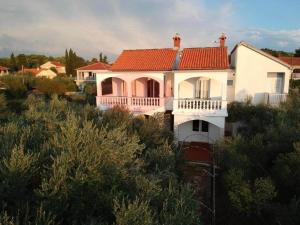 una casa blanca con techo rojo en una colina en Family House Rebeka en Ugljan