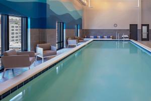 a swimming pool in a hotel room with chairs at Hyatt House Indianapolis Downtown in Indianapolis