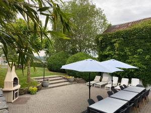 een groep tafels en stoelen met parasols bij Suzanne's Cottage in Rochehaut