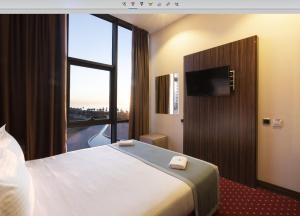 a hotel room with a bed and a large window at Legend Business Hotel Batumi in Batumi