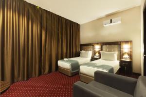 a hotel room with two beds and a couch at Legend Business Hotel Batumi in Batumi