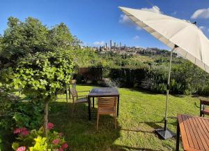 una mesa y sillas bajo una sombrilla en un patio en B&B Il Fienile San Gimignano, en San Gimignano