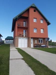 a large orange house with a white garage at Apartments Millenium in Žabljak