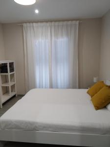 a bedroom with a large white bed and a window at Ca la Lola in L'Escala