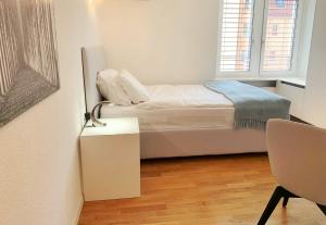 a small white bedroom with a bed and a table at Guesthouse Lochergut in Zürich
