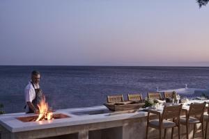 un homme debout à côté d'un foyer extérieur avec l'océan dans l'établissement Villa Santa Katerina - Sea View & Outdoor Hot Tub, à Platis Gialos