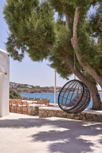a swing hanging from a tree next to the water at Villa Santa Katerina - Sea View & Outdoor Hot Tub in Platis Yialos Mykonos