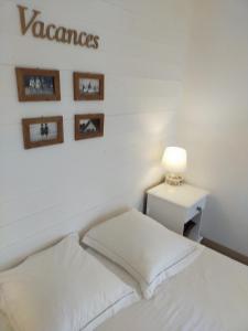 a white bedroom with a bed and a table with a lamp at Chambre d'hôtes Larosa in Moulis-en-Médoc