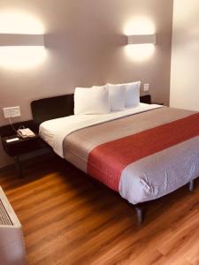 1 dormitorio con 1 cama grande y suelo de madera en Motel 6-Augusta, GA - Fort Gordon en Augusta