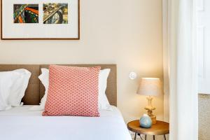 a bedroom with a bed with a red pillow and a table at Jardins da Muralha Apartments by DA'HOME in Porto