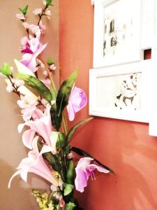 a vase with pink flowers on a wall with a picture at B&B Centro900 in Palermo