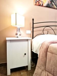 a white nightstand with a lamp on it next to a bed at B&B Centro900 in Palermo