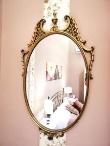 un espejo de oro grande colgando en una pared de un dormitorio en B&B Centro900, en Palermo