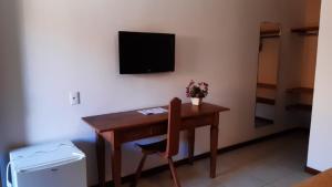 a desk with a chair and a television on a wall at Palmier Hotel & Convenções in Itaboraí