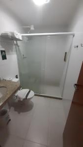 Baño blanco con aseo y lavamanos en Palmier Hotel & Convenções en Itaboraí