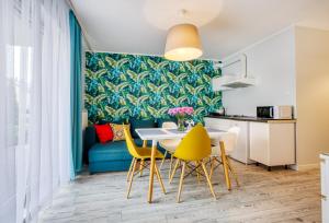 Apartamenty Olivia في فواديسوافوفو: مطبخ وغرفة طعام مع طاولة وكراسي صفراء