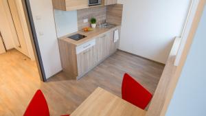 una pequeña cocina con sillas rojas y mesa en A2 Boarding House Memmingen, en Memmingen