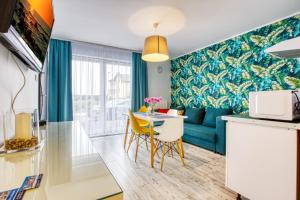 Apartamenty Olivia في فواديسوافوفو: غرفة معيشة مع أريكة زرقاء وطاولة مع كراسي صفراء