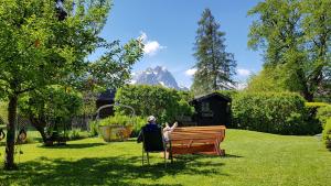 une femme assise sur un banc dans un parc dans l'établissement Hilleprandt - Adults Only, à Garmisch-Partenkirchen