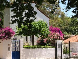 una cerca blanca frente a una casa con flores rosas en Spiti Galini, "Haus der Zufriedenheit", en Paralía Sergoúlas