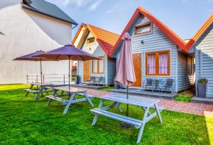 un grupo de mesas de picnic con sombrillas frente a una casa en Domki Olivia, en Władysławowo