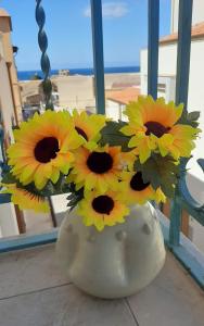 a white vase filled with yellow flowers in a window at La Melagrana in Castellammare del Golfo